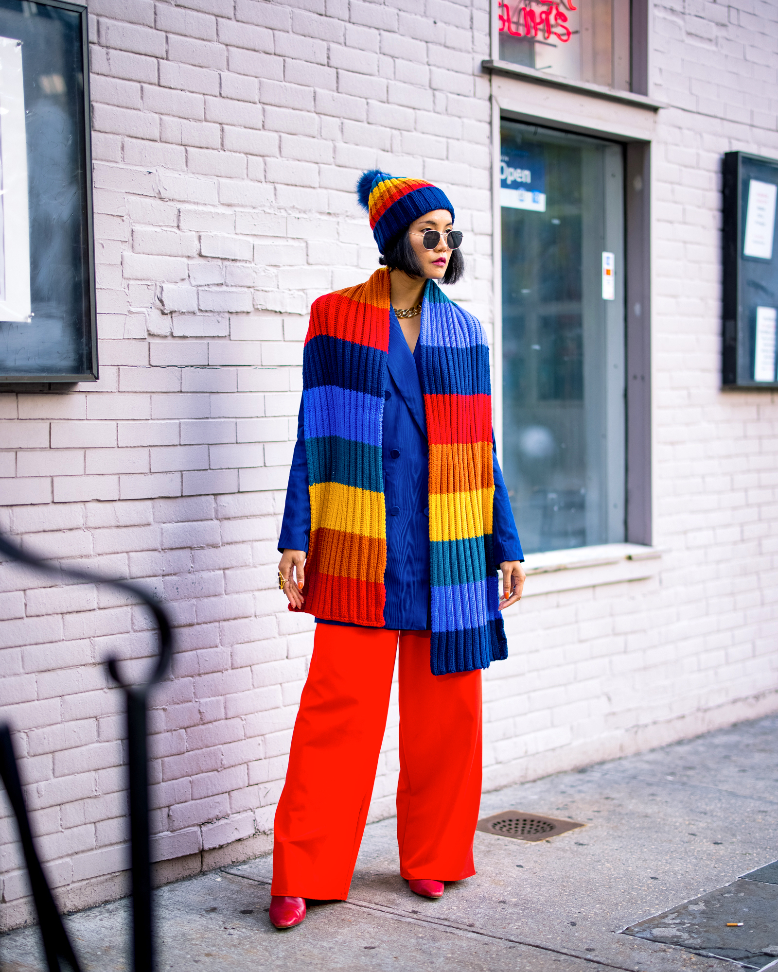 easy ways to style a striped rainbow chunky knitted scarf for winter by wearing it as a cape over your shoulders
